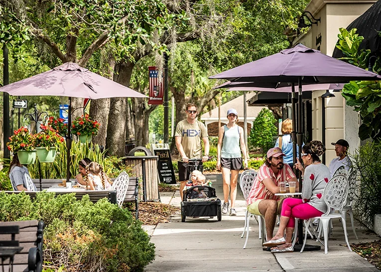 people walking down shopping street and sitting at a cafe